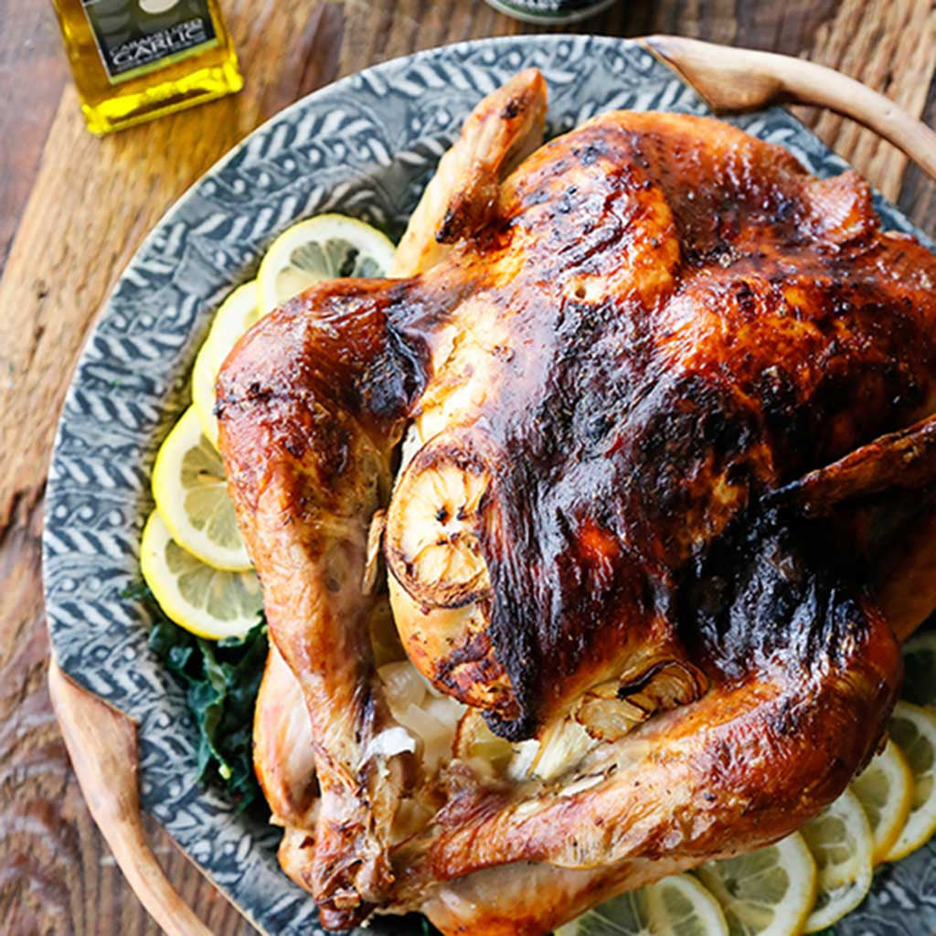 Garlic and Lemon Greek Roasted Turkey accompanied by lemon slices served on a blue platter a top a wooden table top